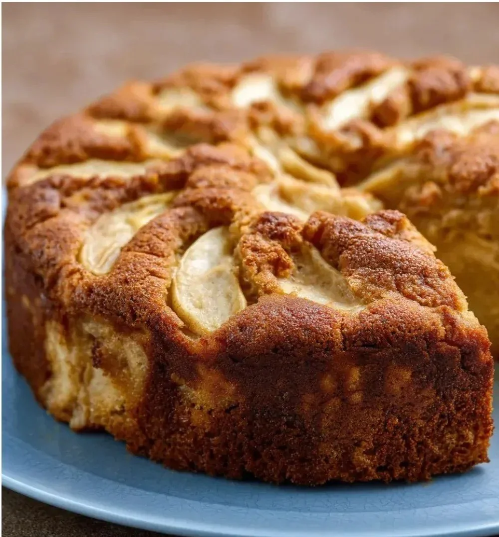 Apfelkuchen mit Kastanienmehl auf einem rustikalen Holzbrett serviert.