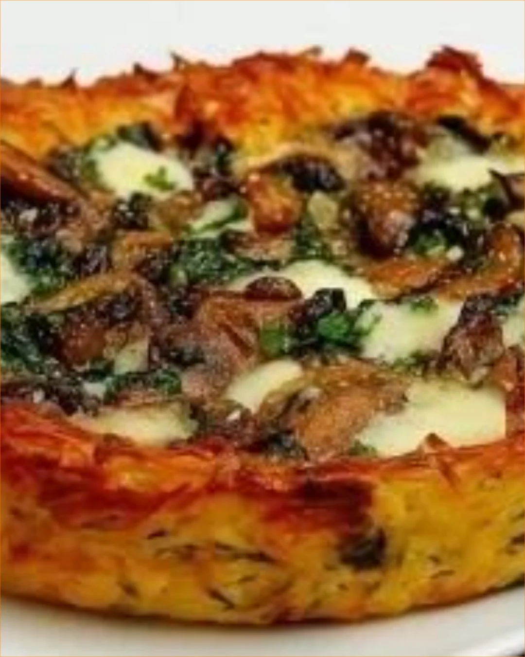 Kartoffelkuchen mit Pilzen und Spinat auf einem Teller angerichtet