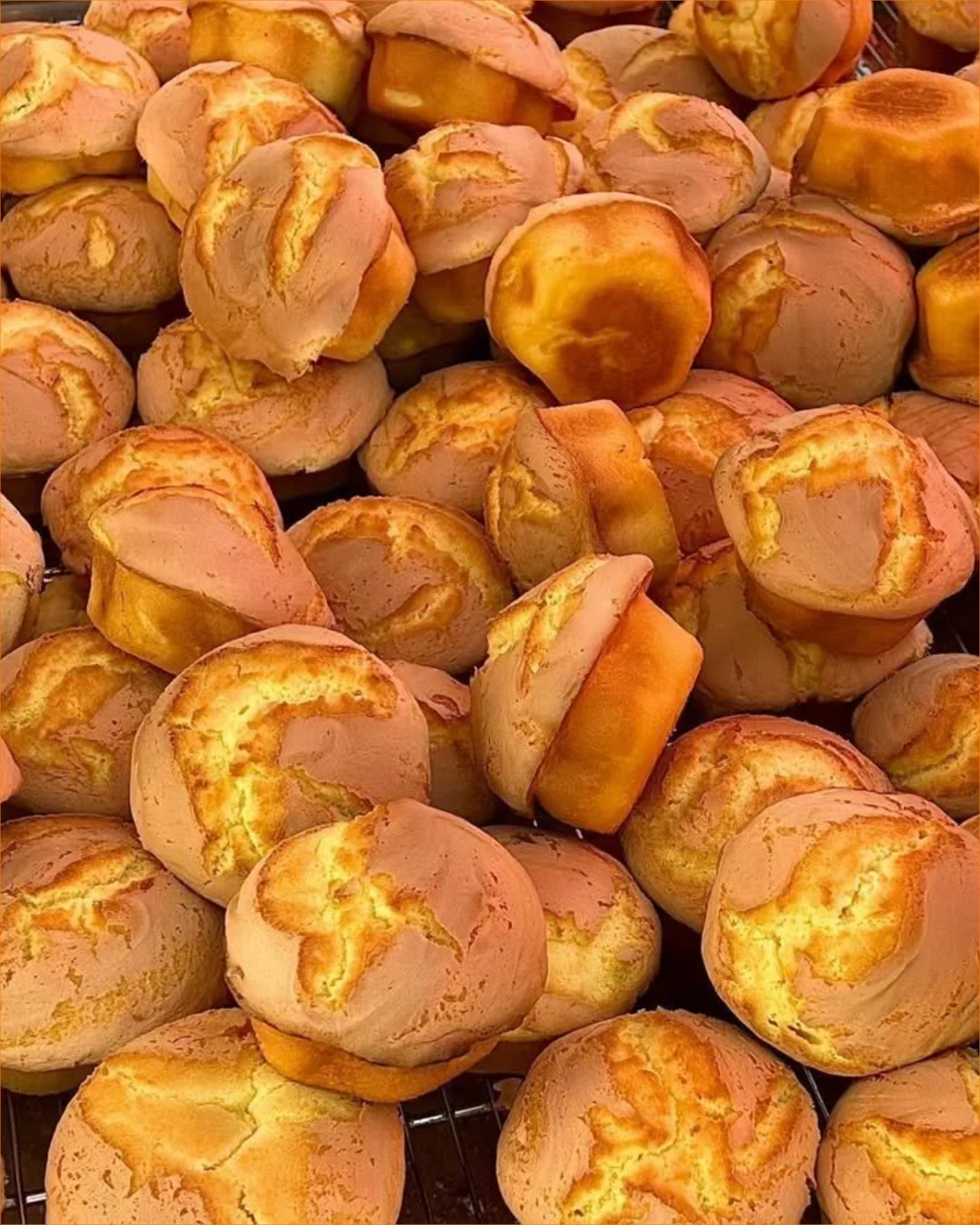 Frisch gebackene Vanille-Muffins auf einem Blech mit Puderzucker bestreut.